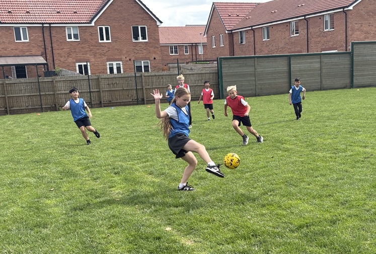 pupils playing a game of football on the school field