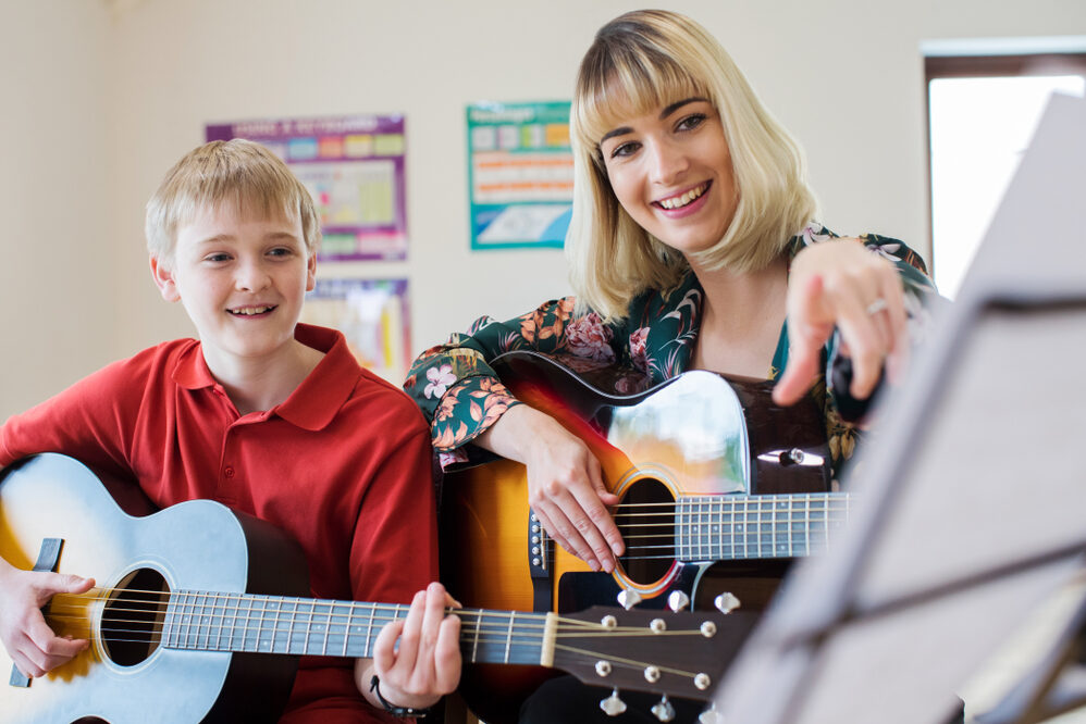 pupil with teacher learning guitar
